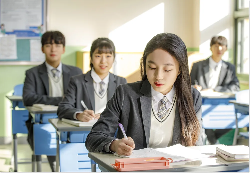 교실에서 교재를 보며 필기하는 학생들