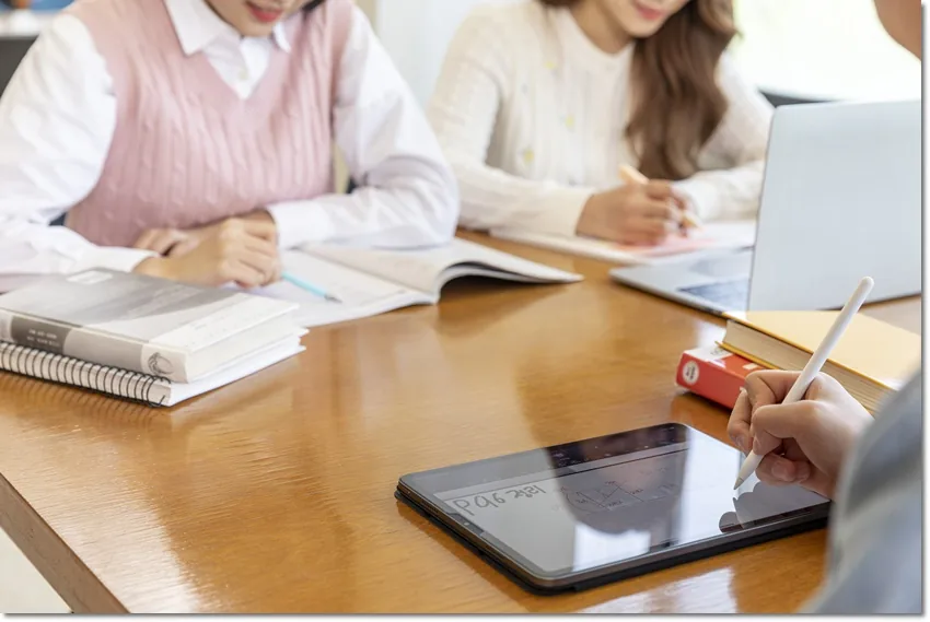 태블릿과 교재를 함께 살펴보는 손