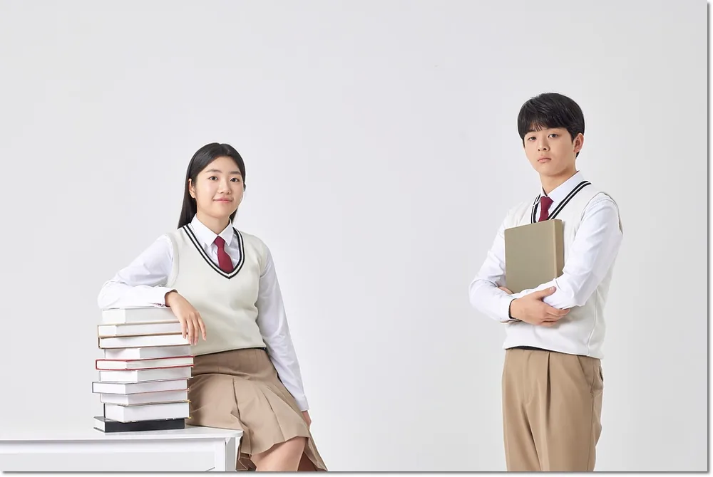 쌓인 책 옆의 두 학생